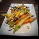 Roasted carrots with herbs, nuts, and sauce on a white rectangular plate.