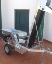 Macchina agricola metallica su ruote, posizionata su un pavimento in cotto vicino a una porta verde.