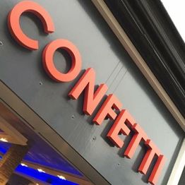 Bord met het woord "CONFETTI" in rode letters op een grijze achtergrond.