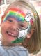 Mädchen mit Einhorn- und Regenbogen-Gesichtsbemalung lächelt glücklich.