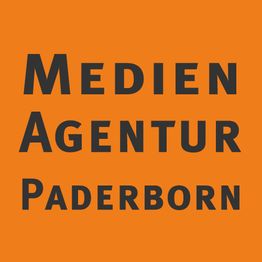 Orange Hintergrund mit schwarzem Text: "Medien Agentur Paderborn".