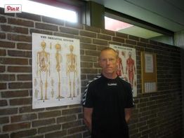 Mand foran murstensvæg med plakater af skeletsystemet.