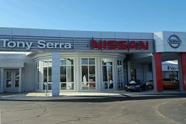 Front view of a Nissan car dealership with clear skies.
