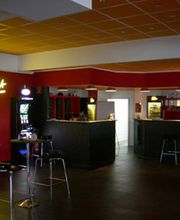 Bar mit rotem Interieur und Neonlicht, leere Hocker an der Theke, gemütliche Atmosphäre.