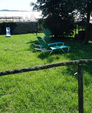 Jardín con césped, dos tumbonas, cobertizo y tobogán azul al fondo, rodeado de setos.