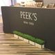 Sign reading "Peek's since 1969" with planters in front on a wooden floor.