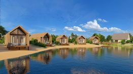 Moderne houten huisjes aan een meer, omgeven door natuur en een blauwe lucht.
