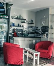 Kleine Lounge mit zwei roten Sesseln, Kühlschrank, Tisch und Wendeltreppe.