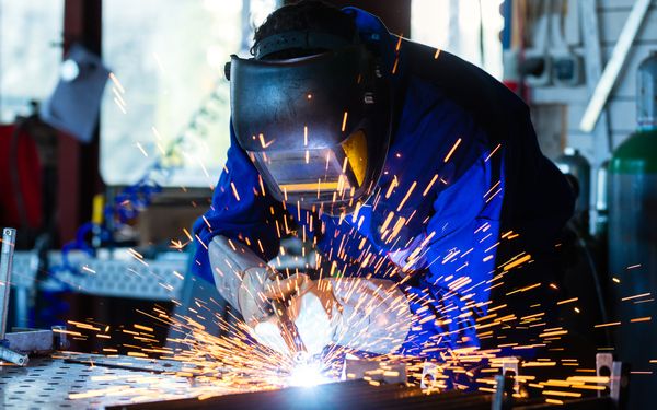 Ein Schweißer schweißt Metall an Metall.