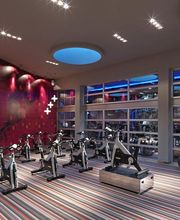 Gimnasio moderno con bicicletas de spinning y decoración colorida en la pared y el suelo.