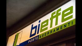 Insegna con scritta "bieffe PORTE & SERRAMENTI" in verde e blu.