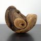 Holzskulptur mit natürlichen Texturen und runden Formen, steht auf einem Metalltisch.