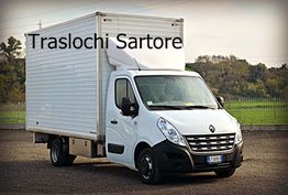 Furgone bianco con scritta "Traslochi Sartore" sullo sfondo di un paesaggio verde.