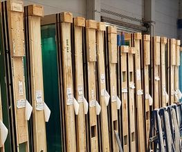 Große Glasplatten in Holzrahmen stehen in einer Lagerhalle nebeneinander aufgereiht.
