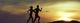 Silhouette von zwei joggenden Personen bei Sonnenuntergang vor einem Bergpanorama.