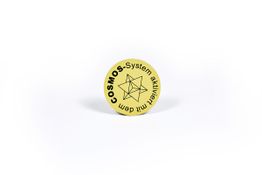 Gelber Knopf mit schwarzem Text "COSMOS-System aktiviert" und einem geometrischen Symbol.