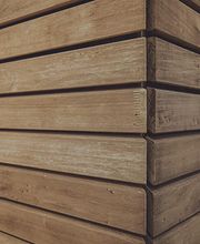 Holzvertäfelte Ecke mit horizontalen Holzlatten, nah aufgenommen.