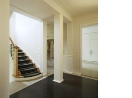 Heller Flur mit schwarzer Treppe und Garderobe; weiße Wände und Türen.