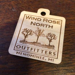 Wooden tag with "Wind Rose North Outfitters, Menominee, MI" and tree design.