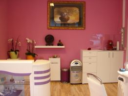 Nagelstudio mit rosa Wänden, weißen Möbeln und Orchideen zur Dekoration.