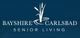 Logo of Bayshire Carlsbad Senior Living with stylized reeds on a dark blue background.