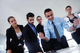 Group of professionals in discussion around a table, focusing on a document.