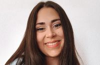 Una mujer joven sonríe con el cabello largo y suelto sobre fondo blanco.