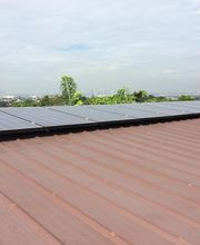 Personas instalando paneles solares en un techo bajo un cielo nublado.