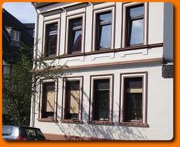 Ein zweistöckiges Gebäude mit mehreren Fenstern und einem Baum davor.