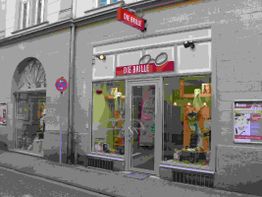 Optikergeschäft mit rotem Schild "DIE BRILLE" über dem Eingang, dekoriertes Schaufenster.