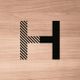 Letter H met zwart-witte lijnen en massieve rechterkant op een houten achtergrond.