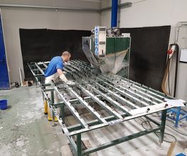 Person arbeitet an einer großen Metallmaschine in einer Werkstatt.