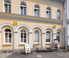 Gelbes Gebäude mit McDonald's-Logos, runden Fenstern und Sitzbänken davor.