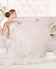 Mujer en vestido de novia blanco con flores, sentada en un sillón, rodeada de decoración elegante.