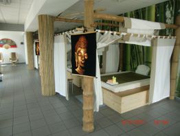Ein Bambus-Pavillon mit Buddha-Bild, Massagetisch und handtuchbedecktem Kopfkissen im Raum.