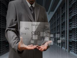 Man in suit holding glass panel with SEO-related words in a server room.