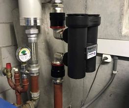 Rohrleitungen und Messgeräte in einem Heizungsraum mit Magnetfilter und Manometer.