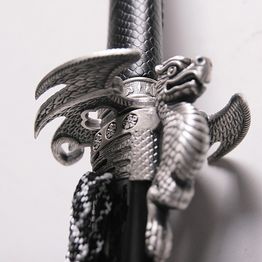 Nahaufnahme eines Schwertes mit silbernem Drachengriff, schwarzer Griff mit feinem Muster.