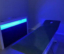 Camilla de masaje en habitación iluminada con luz azul tenue.