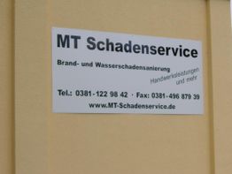 Schild mit Kontaktinfos von MT Schadensservice für Brand- und Wasserschadensanierung.