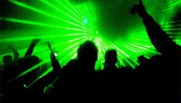 Menschen tanzen in einem Club mit grünen Lasern und Lichtern.