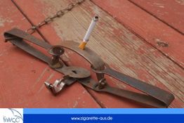 Eine Zigarette in einer Bärenfalle auf Holz.