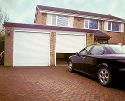 Black car parked in front of a house with two open garage doors.