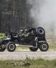 Vehículo todoterreno militar con dos personas, avanzando en un terreno con humo detrás.
