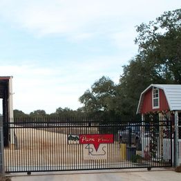 Entrance gate to a farm with a barn and trees in the background.