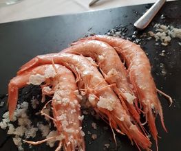 Camarones con sal gruesa sobre una tabla negra.