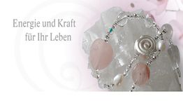 Kristall mit Schmuck, Text: "Energie und Kraft für Ihr Leben", rosa Hintergrund.