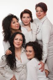 Fünf Frauen in weißer Kleidung posieren zusammen freundlich für die Kamera vor weißem Hintergrund.