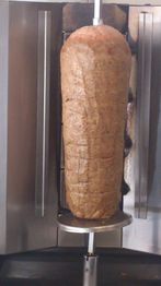 Carne asándose verticalmente en un trompo para preparar kebabs o gyros.