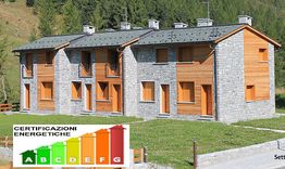 Edifici in pietra con classificazione energetica a fianco. Alberi sullo sfondo.